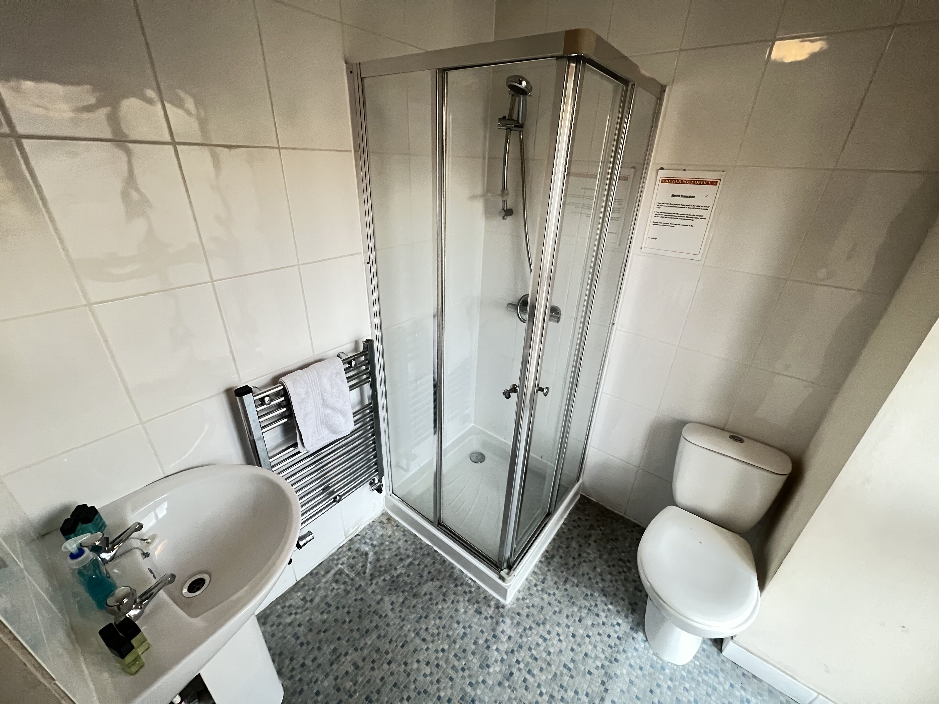 Un baño con cabina de ducha de vidrio, lavamanos blanco y un inodoro.