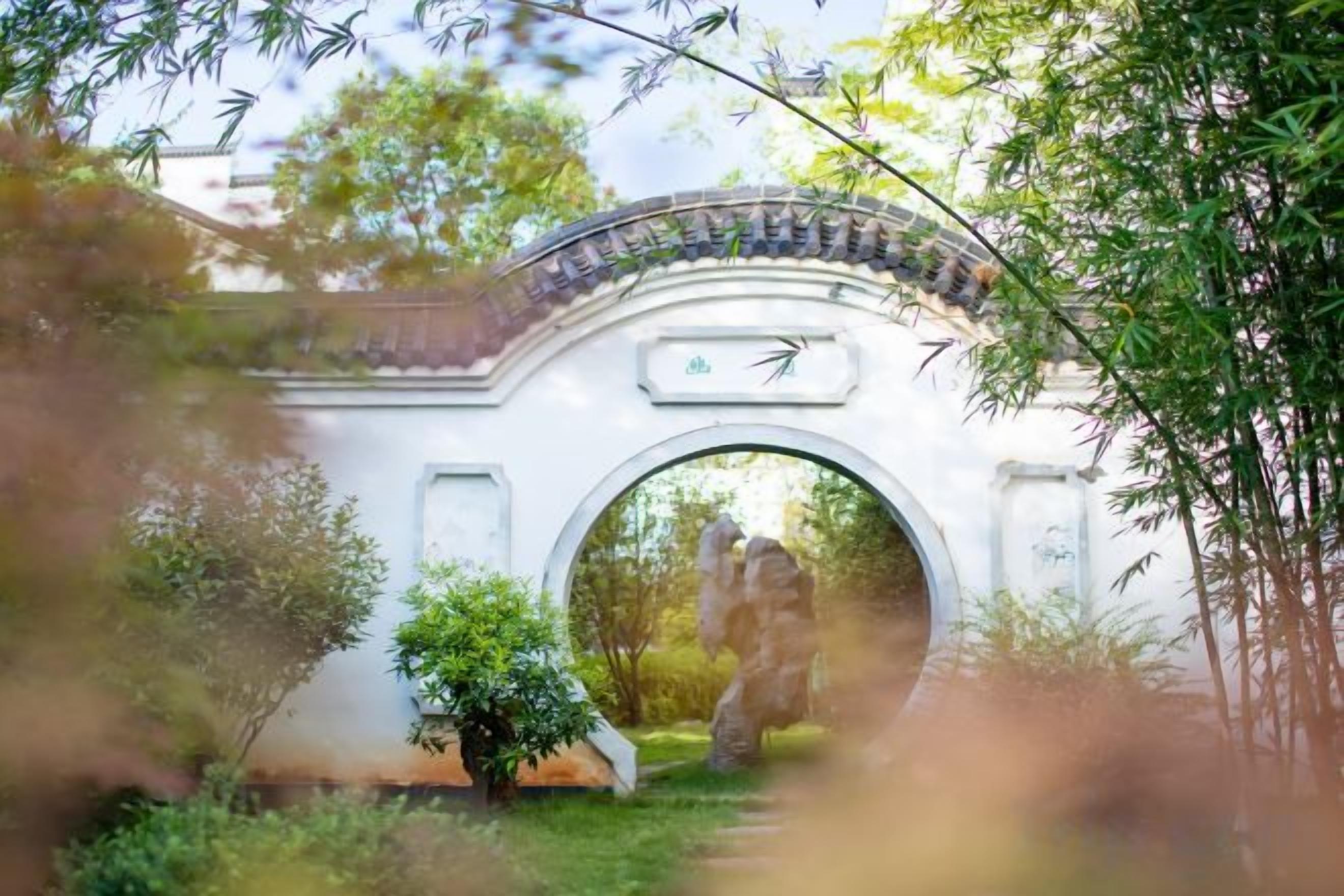A traditional archway with a tiled roof, surrounded by greenery.