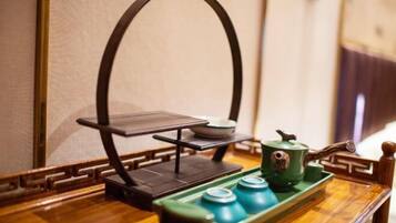 A traditional tea set on a wooden tray with a teapot and cups, placed on a table with a simple stand.