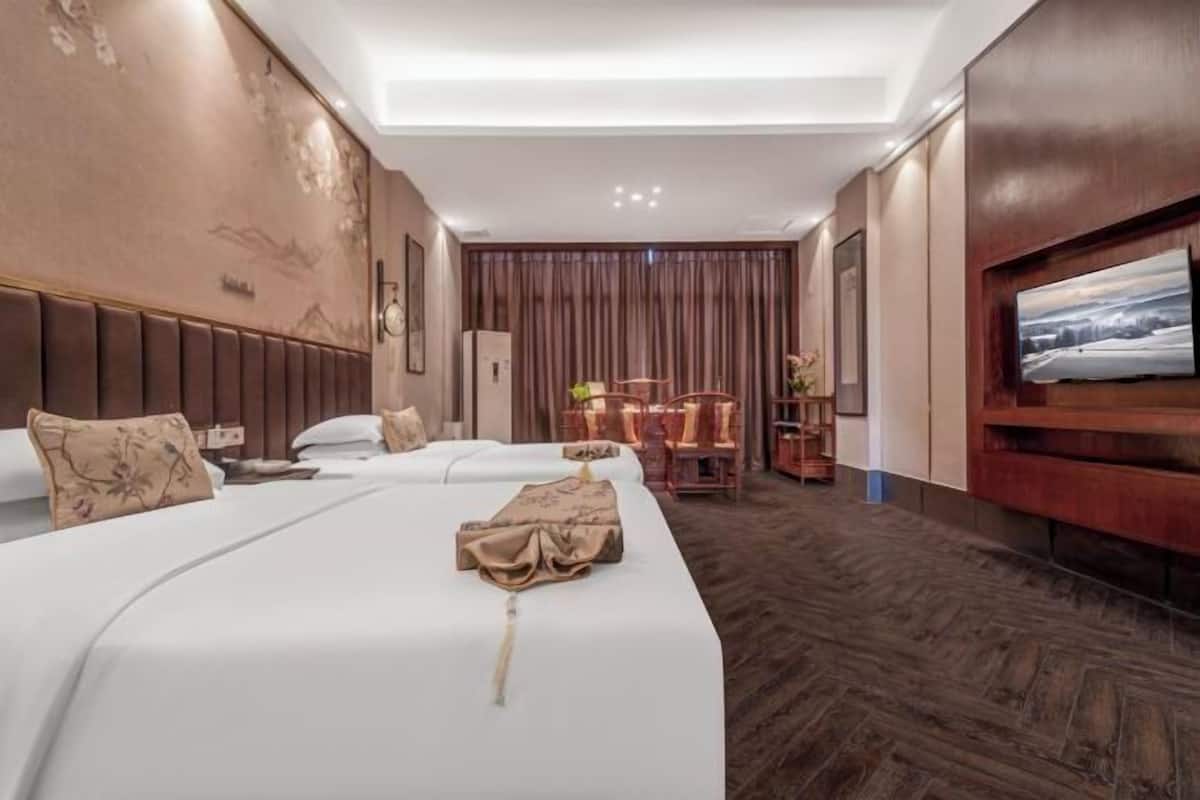 Habitación de hotel con dos camas, televisión, escritorio y una silla.