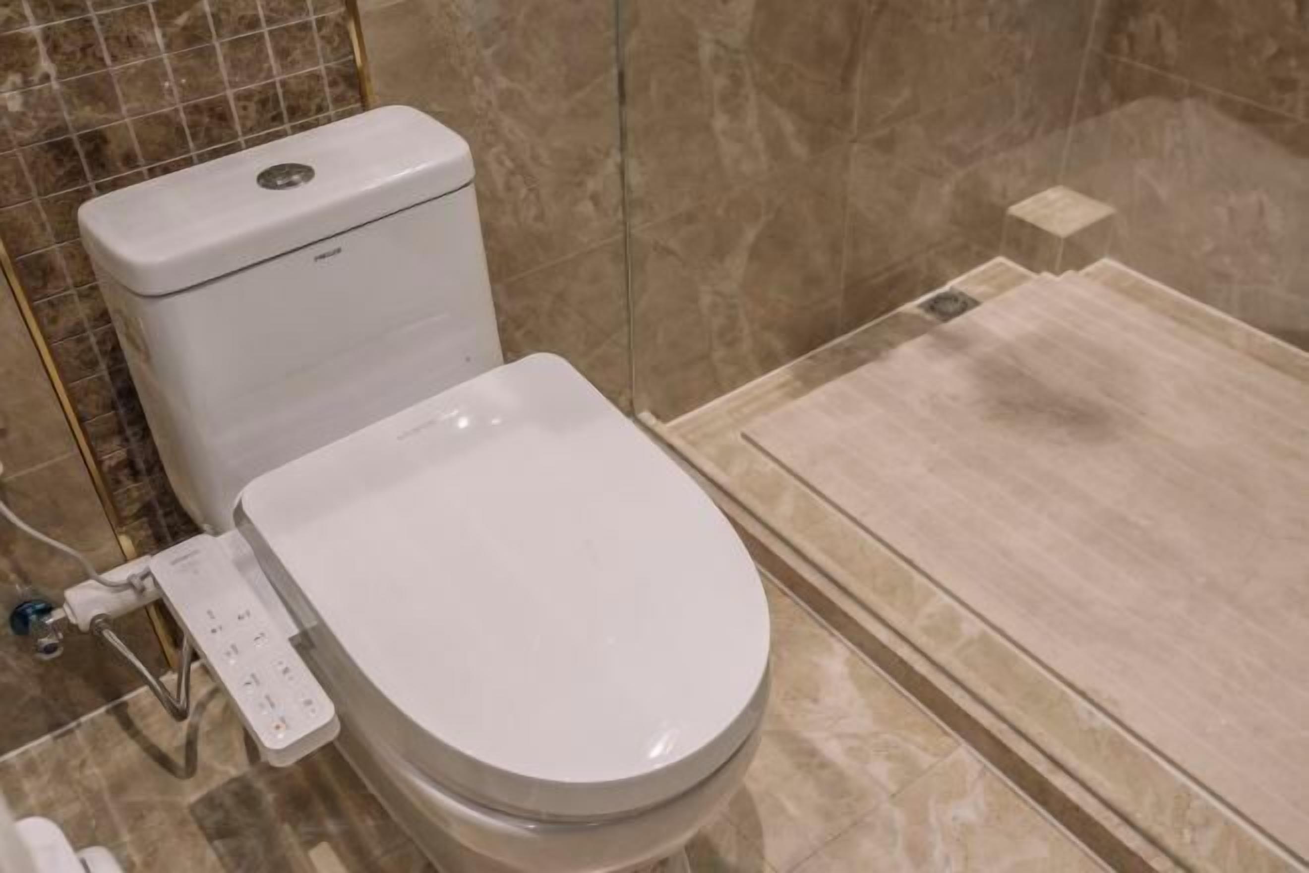 Een moderne badkamer met een toilet, een douche en een hygiëneslot.