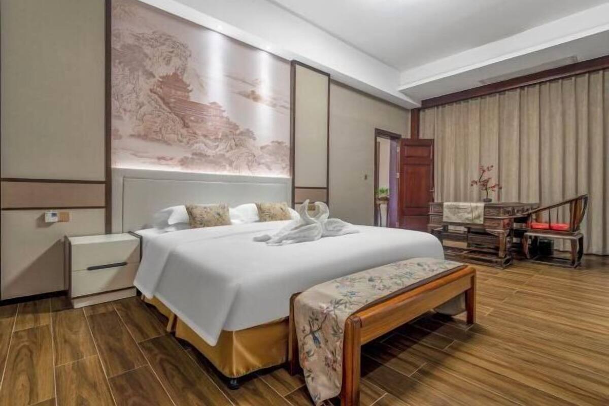 Habitación de hotel con cama, un banco, un escritorio y un cuadro grande en la pared.