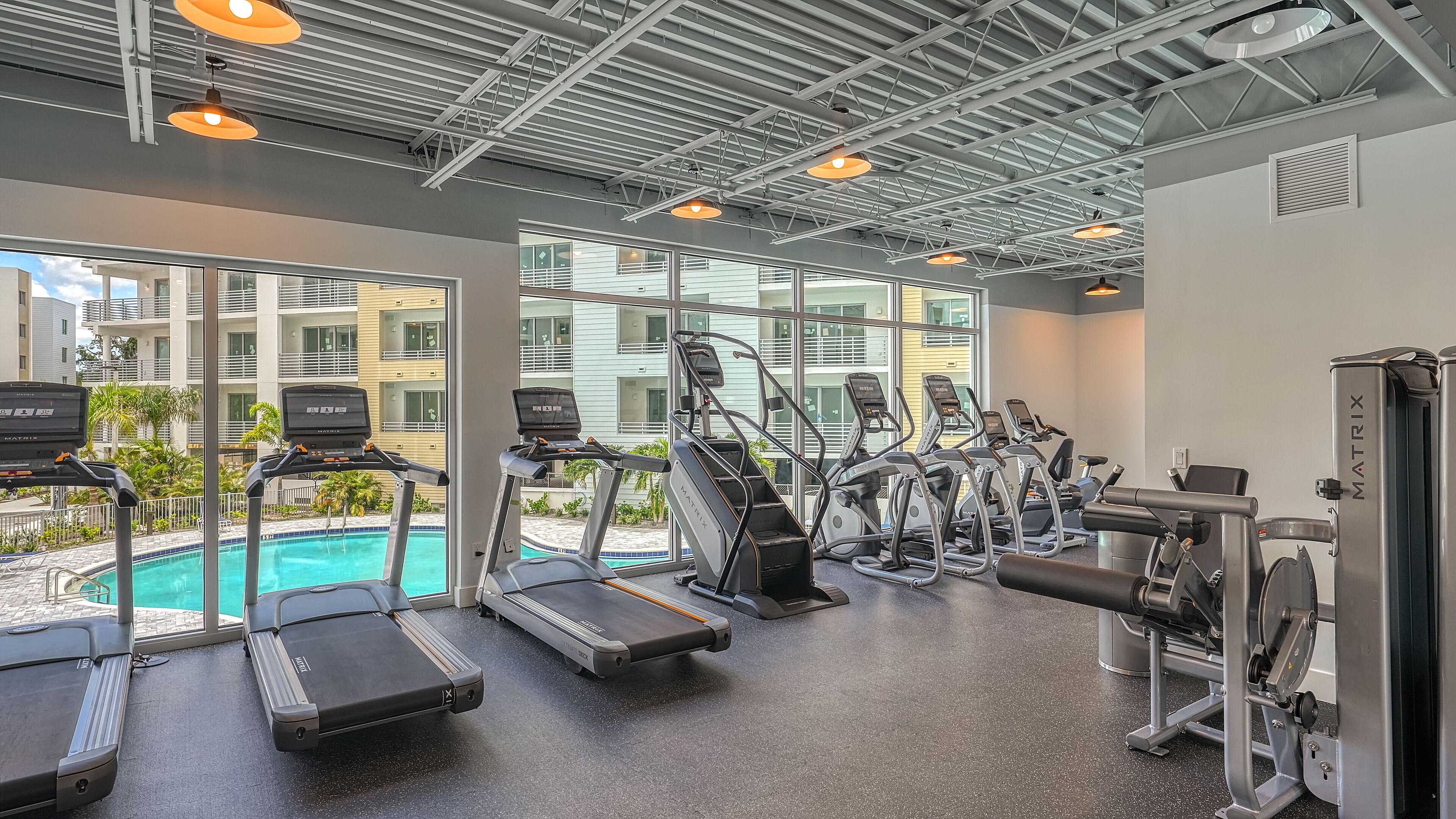 Une salle de sport équipée de tapis de course, de vélos elliptiques et de matériel de musculation.