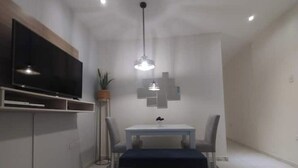 Et moderne køkken med indbygget TV, spisebord med stole og en hængende pendel.