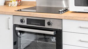 Eine Küche mit Backofen aus Edelstahl, einer Mikrowelle und einer Holz Arbeitsplatte.