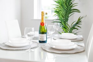 Et spisebord dækket med hvide tallerkener, en flaske af vintage Codorniu champagne og tomme vinglas.