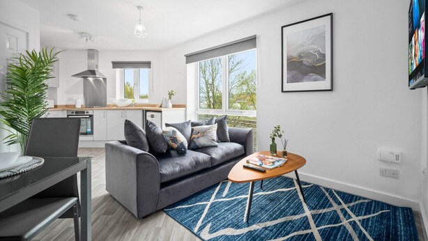 Una sala de estar moderna con un sofá gris, una mesa de centro de madera y una alfombra azul.