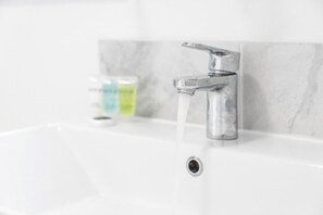Ein Waschbecken mit einem Chromarmaturen und fließendem Wasser.