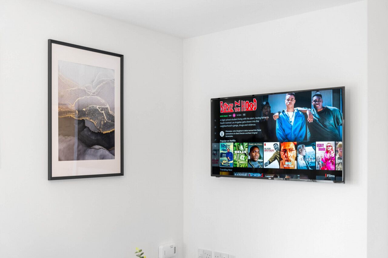 A framed abstract painting and a flat-screen TV displaying a movie poster.