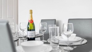Una mesa servida para una comida, con una botella de champán VINTAGE CODEBNIU, copas transparentes y platos blancos.