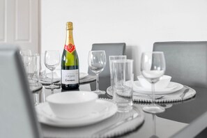 Ein gedeckter Tisch mit einem Bouteille VINTAGE CODEBNIU Champagner, klaren Gläsern und weißen Tellern.