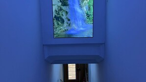 A hallway with a large digital screen displaying a waterfall. - ŞİRİNYER ELİT RESİDANCE APART HOTEL (Izmir)