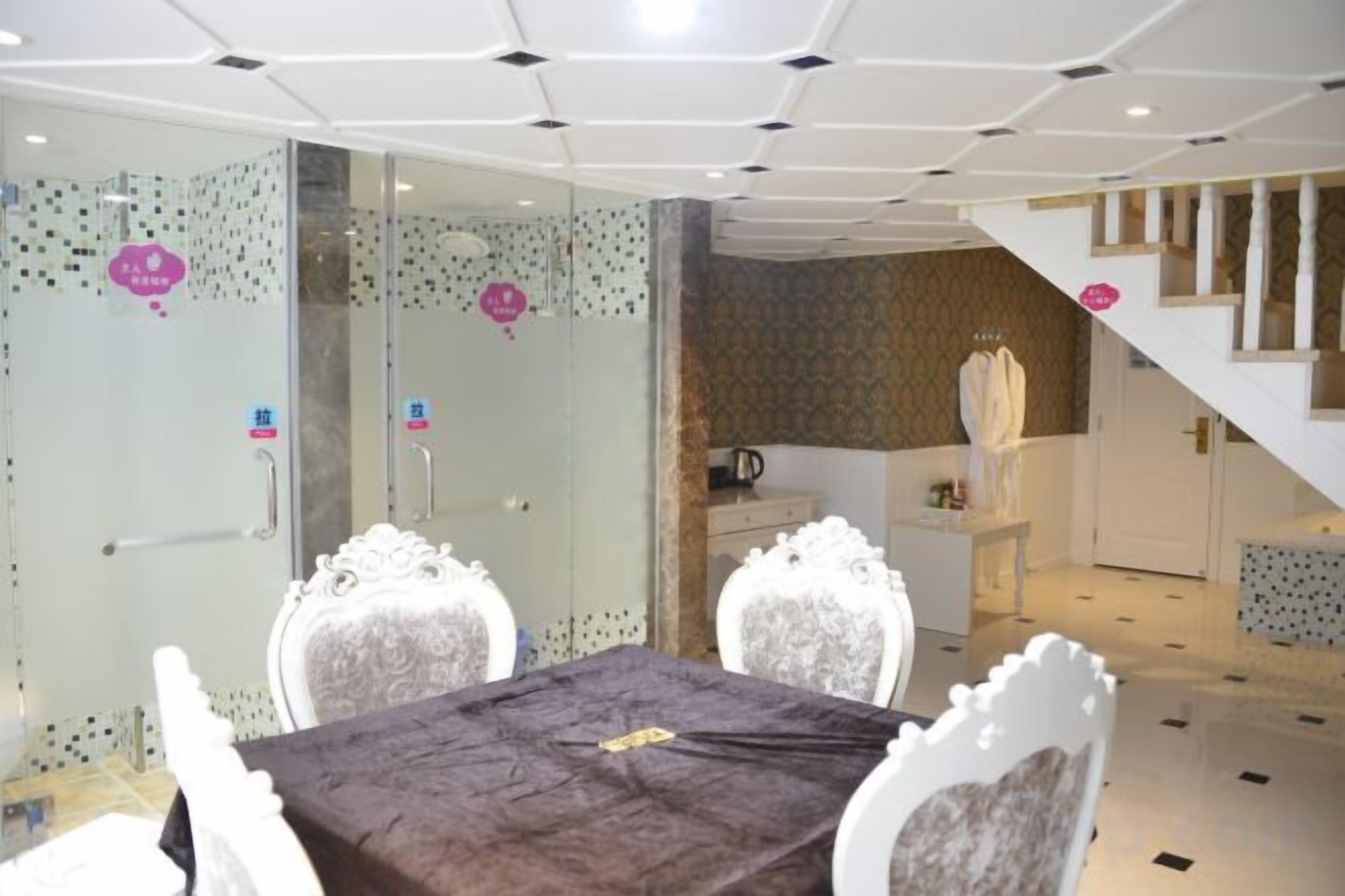 A hotel room with a dining area featuring a table and chairs, a staircase, and a view of the outside.