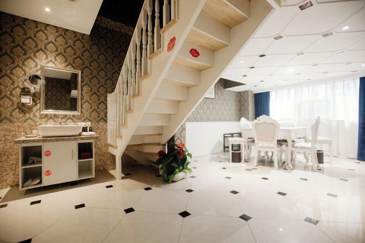 A modern hotel room with a bathroom, a dining area, and a staircase.