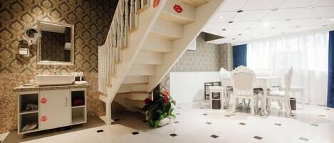 A modern hotel room with a bathroom, a dining area, and a staircase.