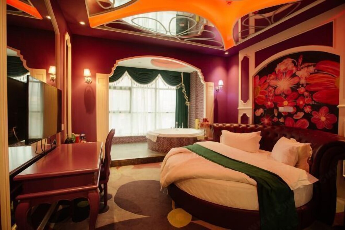 A room with a bed, a desk, and a window with curtains.