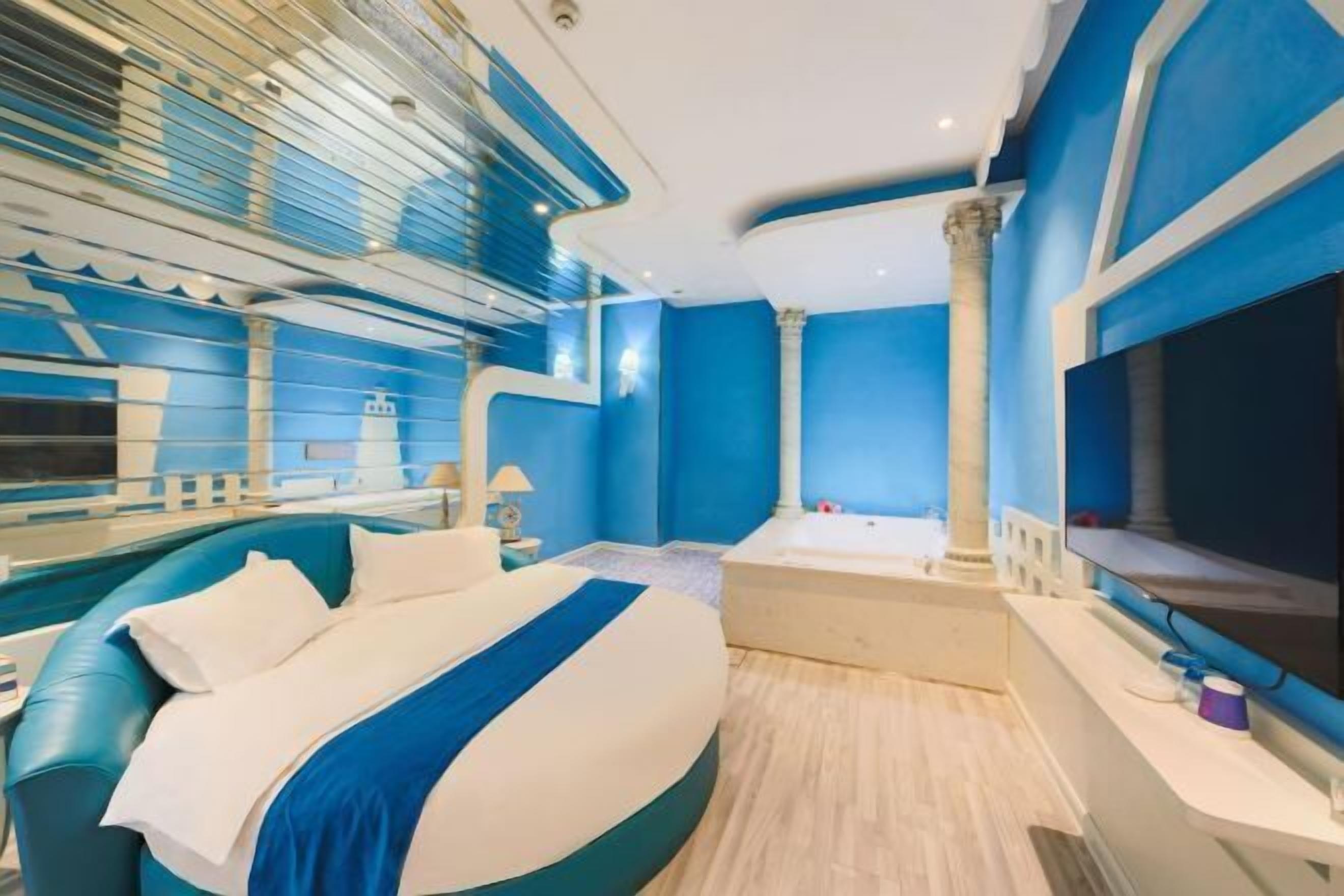 Quarto moderno com cama sinuosa, uma janela ampla e uma banheira.