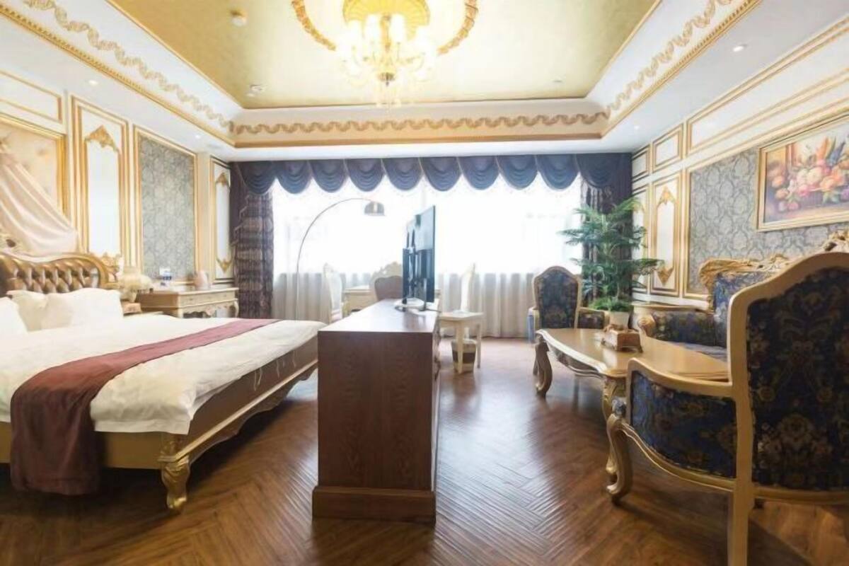 A luxurious hotel room with a large bed, a desk, and a television.