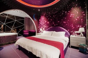 A modern bedroom with a bed, a curved seating area, and a wall with a starry design. - Xiaowang Kingdom Theme Hotel (Shiyan Railway Station North Square Beijing South Road Branch) (Shiyan)