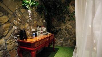 Una habitación con pared de piedra, cómoda de madera y alfombra verde.