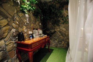 Une pièce avec un mur en pierre, une commode en bois et une moquette verte.