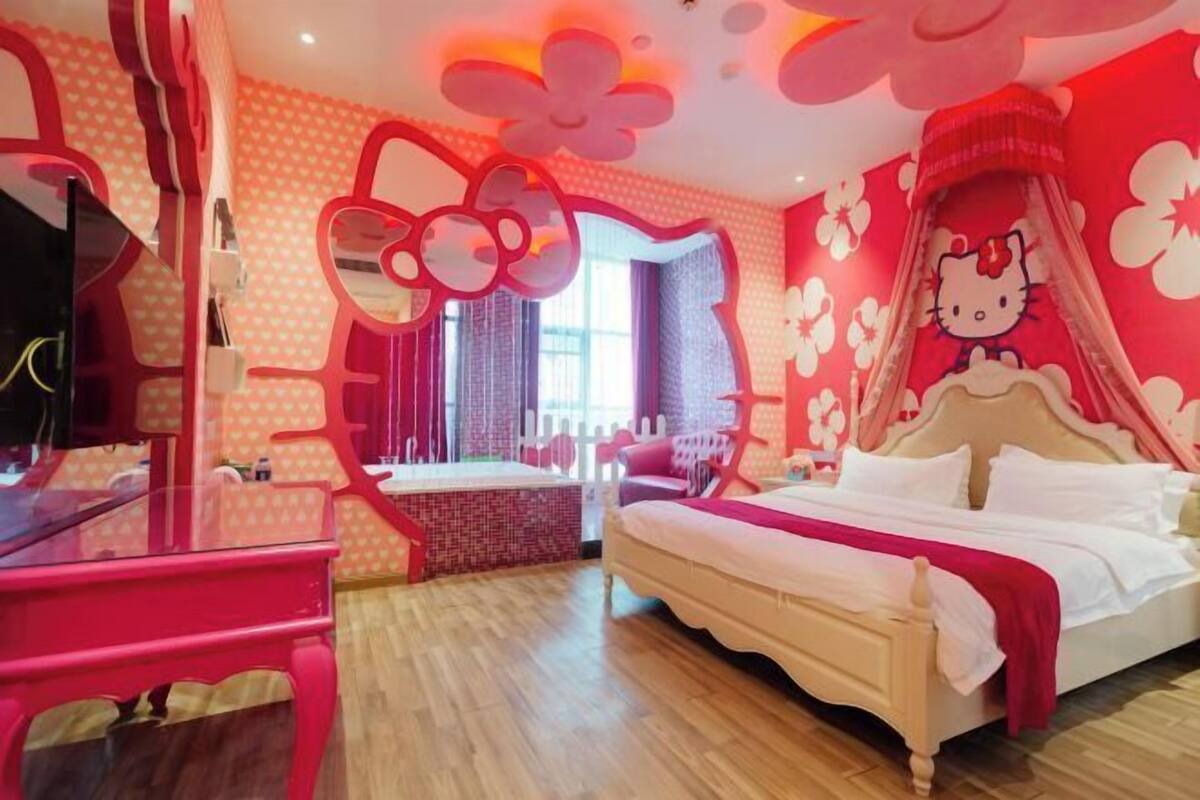 A room with a bed, a desk, and a chair. There is a window with curtains.