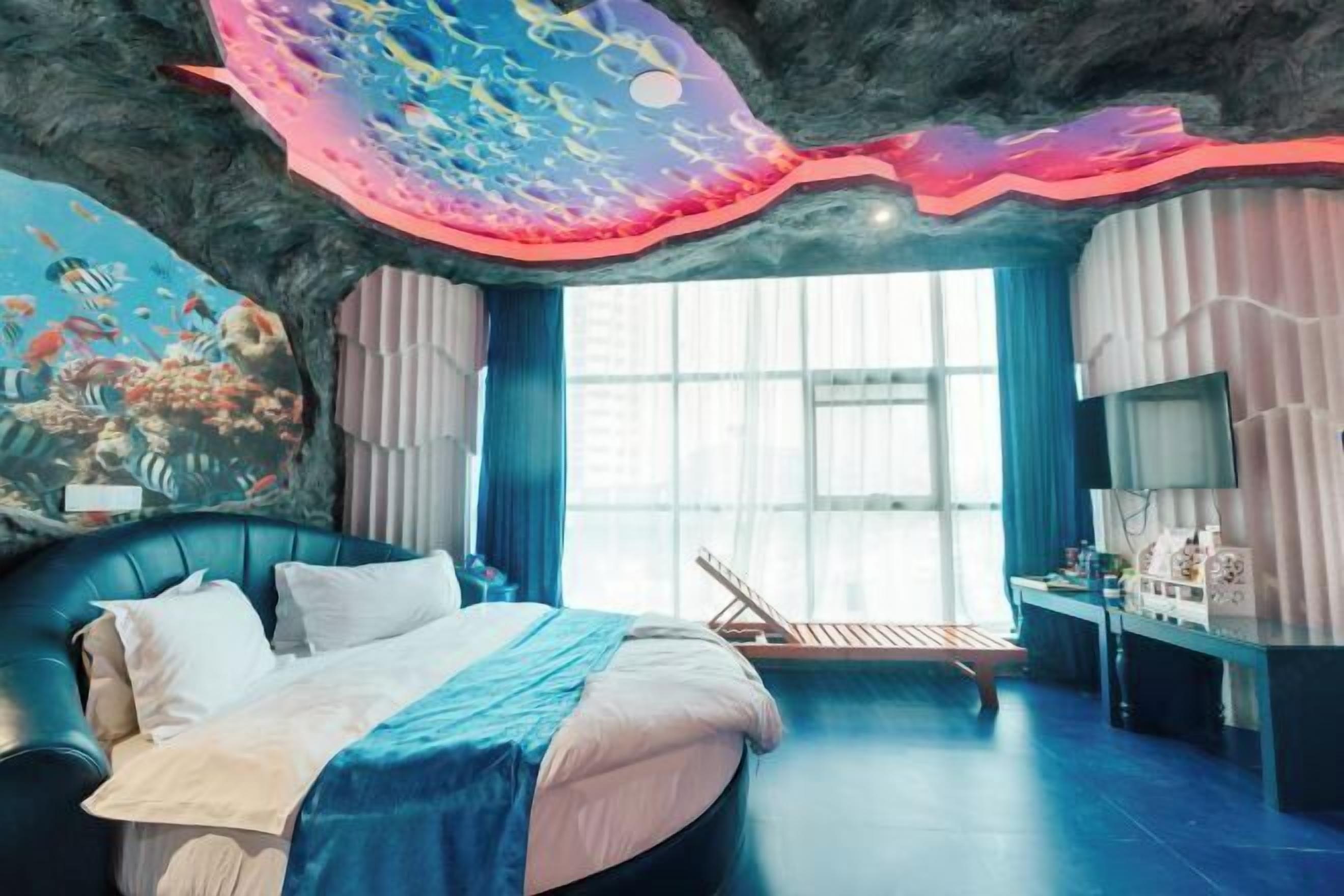 Een moderne slaapkamer met een groot bed, een muurschildering van vissen en uitzicht op de stad.