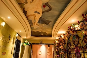 Un hall de hotel con techo decorativo, una recepción y arreglos florales.