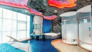 Una habitación de hotel moderna con una cama grande, una zona de estar, una bañera y un espacio con ducha.