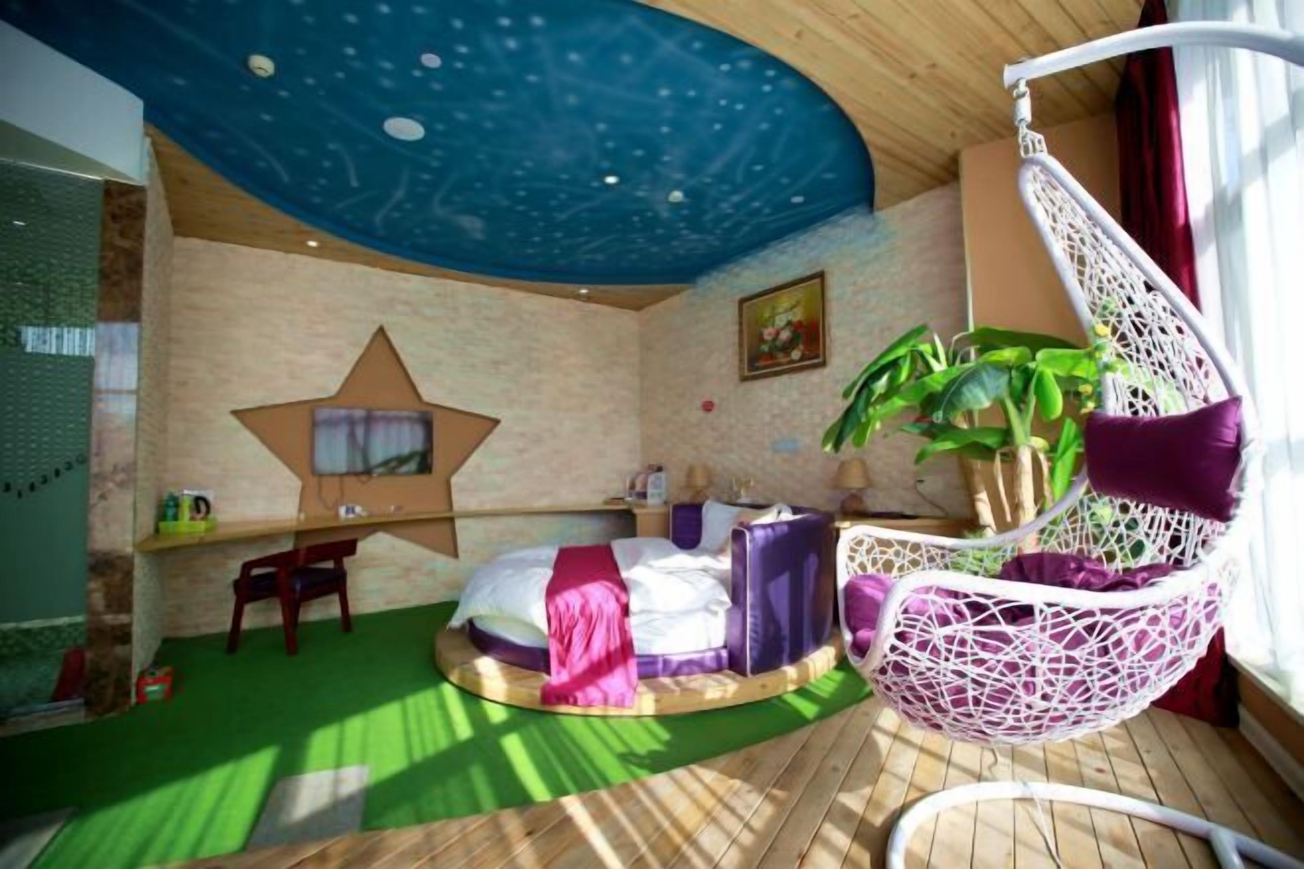 A room with a star-shaped wall decoration, a bed with a purple headboard, a hanging chair, and a potted plant.
