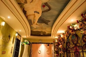 A hotel lobby with a decorative ceiling, a reception desk, and floral arrangements. - Xiaowang Kingdom Theme Hotel (Shiyan Railway Station North Square Beijing South Road Branch) (Shiyan)