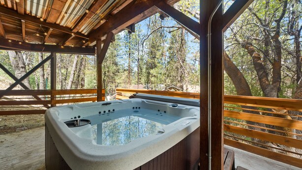 Ein Whirlpool auf einer Holzterrasse mit Blick auf Bäume.