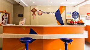 A hotel reception desk with a logo, a computer, and a fruit bowl. - 99 Inn Chain (Changshu Fangtayan Baibaiban) (Changshu)