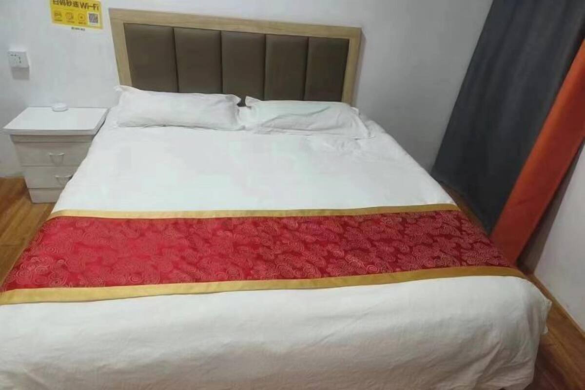 A bed with a headboard, a bedside table, and a red decorative item on the bed.