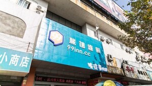 A hotel with a prominent blue sign advertising a 99 Inn. The building has multiple floors with various shops on the ground level. - 99 Inn Chain (Changshu Fangtayan Baibaiban) (Changshu)
