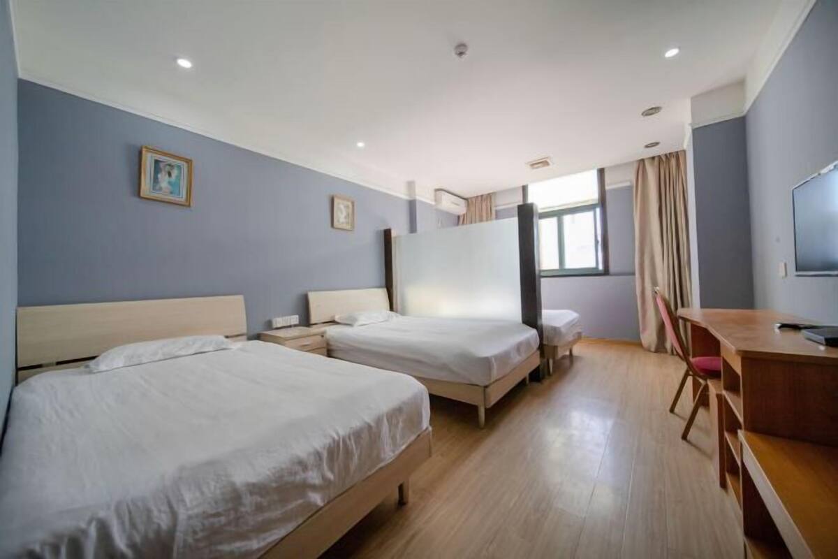 A hotel room with two beds, a desk, and a television.