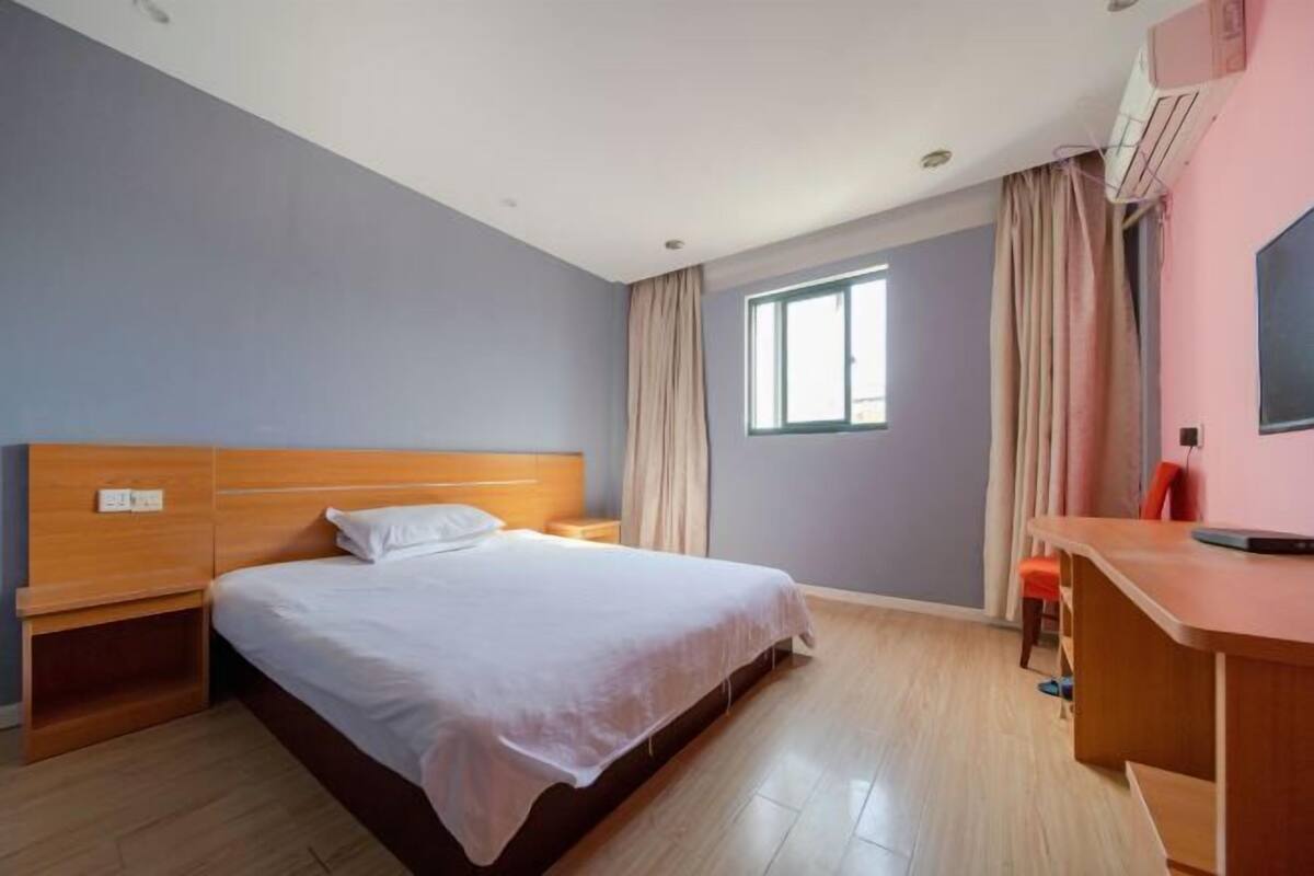 A bedroom with a wooden bed, a desk, and a window.