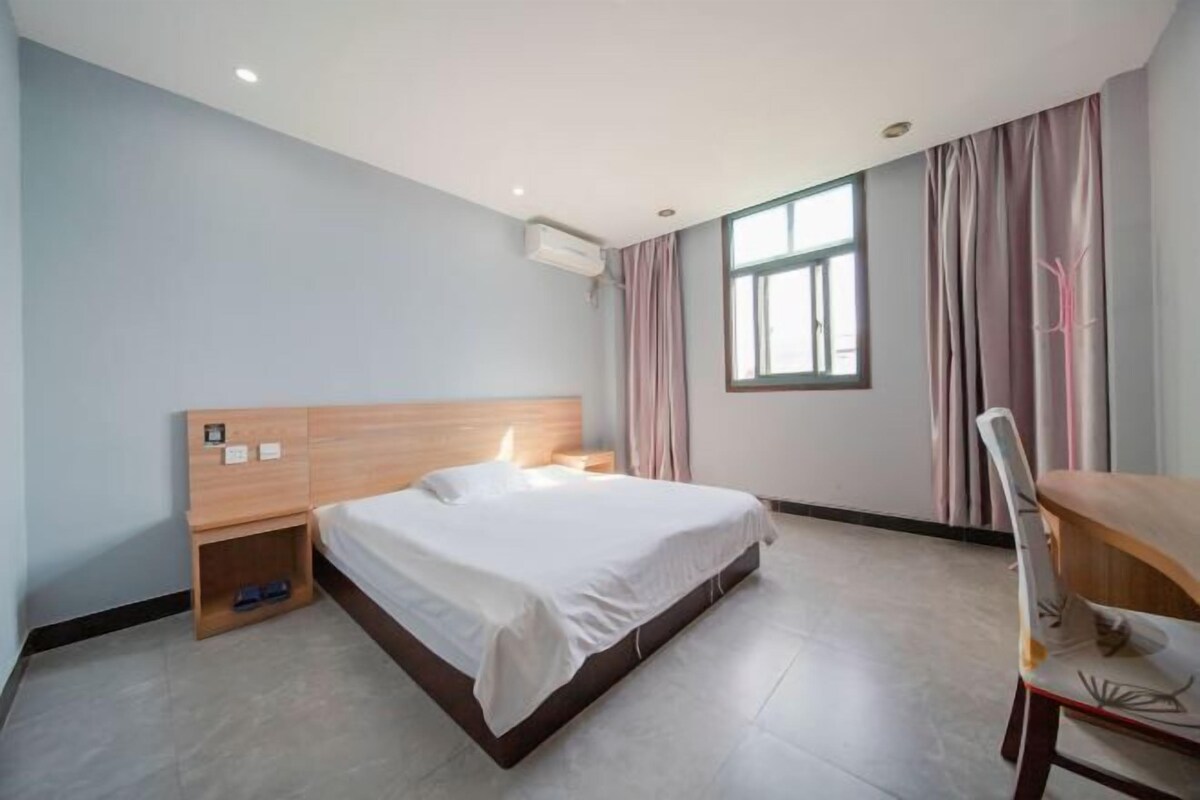 A hotel room with a bed, bedside table, and a chair.