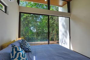 A bedroom with a large bed, a view of a balcony, and a wooden ceiling. - Casa Henaway (Savegre)