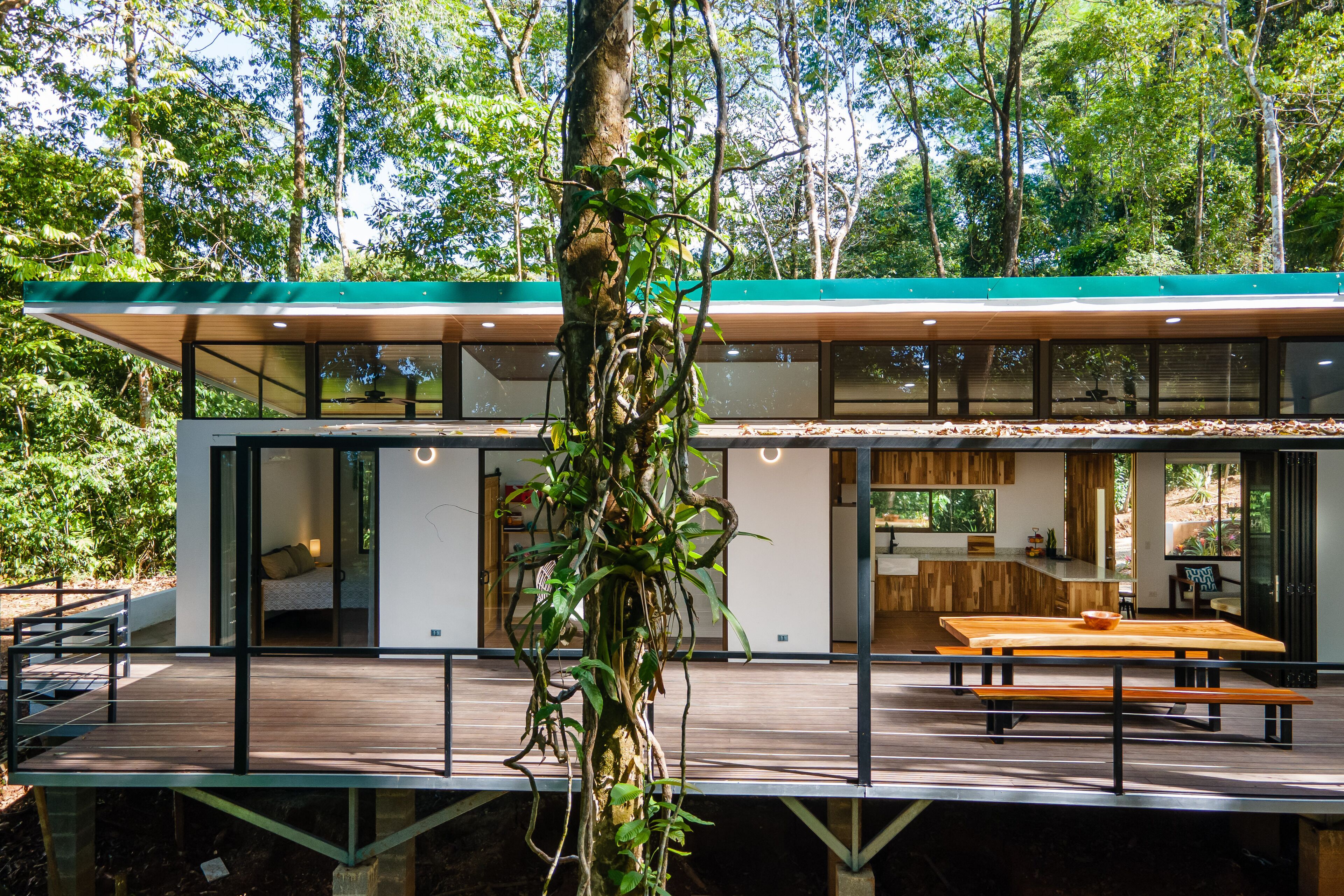 Una moderna casa a due piani con un patio in legno, ampie finestre e un'area cucina.