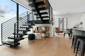 A modern interior with a black staircase, a wooden floor, a bookshelf, a brown leather chair, and a bar area. - Private Pool Oasis, Luxe Amenities, Prime Location, Chefs Kitchen, Skyline Views (Austin)