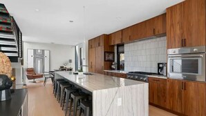 Une cuisine moderne avec des meubles en bois, un îlot en marbre et un four encastré.