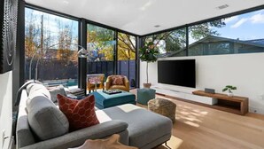 Un salon moderne avec un canapé gris, une table basse et un téléviseur posé sur un meuble en bois.