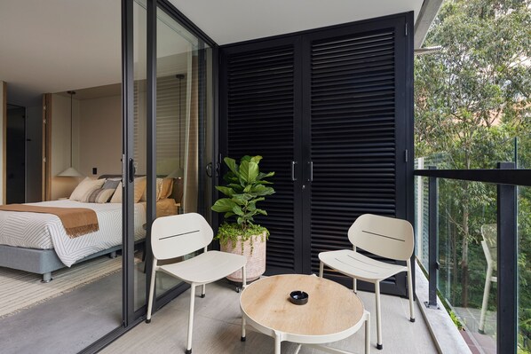Enjoy a serene view from this balcony with a glass door leading to a cozy bedroom.