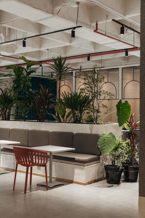 Relax in a stylish seating area with a bench, table, and single chair, surrounded by lush potted plants.