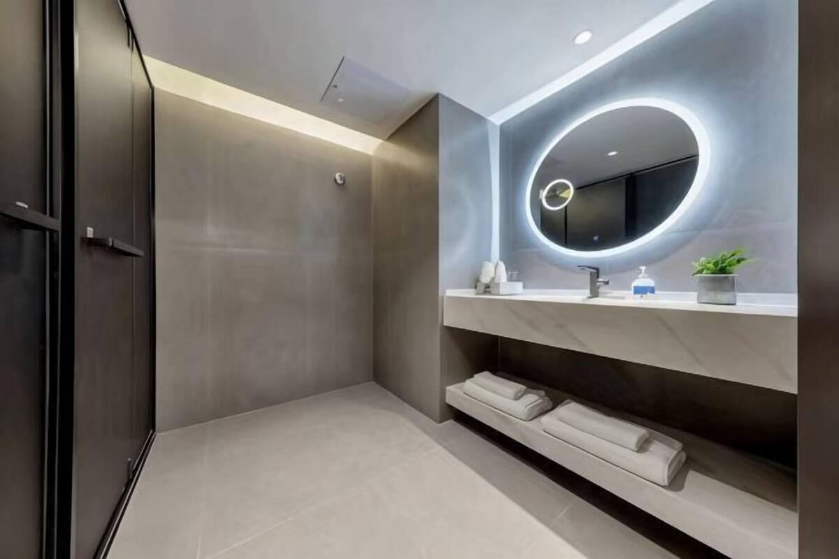 A modern bathroom with a shower, a vanity with a mirror, and a towel rack.