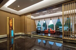 A modern lobby with a reflective floor, seating area with red chairs, and a decorative partition. - Kunming Panlong Days Inn Selected Wyndham Hotel (Agricultural University Branch) (Kunming)