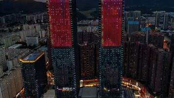 A cityscape with two prominent buildings, one with a red and white sign, and another with a similar sign.