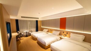 Habitación de hotel con tres camas, un escritorio y una silla.