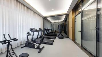 Un gimnasio equipado con cintas de correr, elípticas y una máquina de remo.